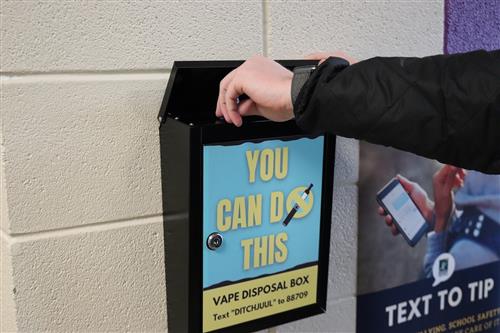 Person dropping a vape into the Vape Disposal Box 